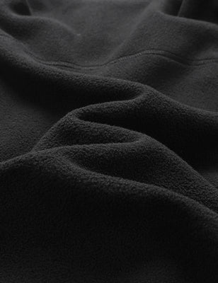 Black fleece vest fabric close-up showing the soft textured surface and folds