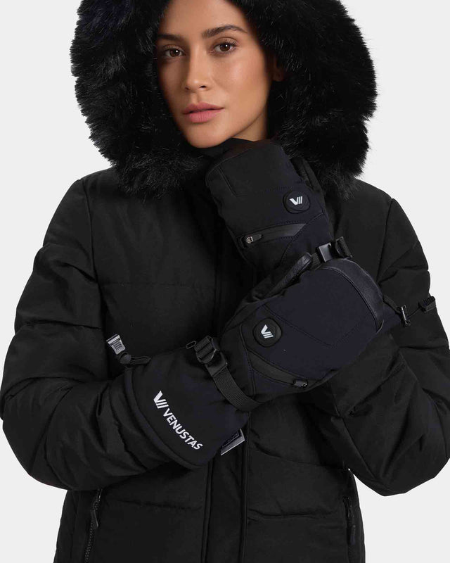 Model wearing black heated mittens with wrist straps and control buttons