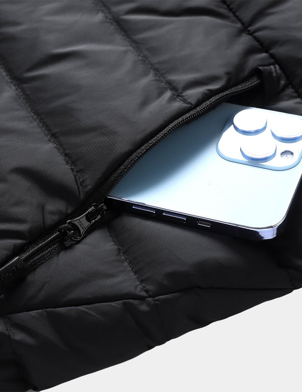 Black quilted heated vest with zippered pocket holding a smartphone