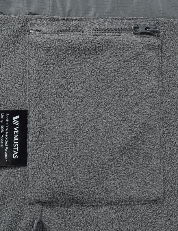 Gray fleece vest close-up showing the zip pocket and recycled polyester fabric label
