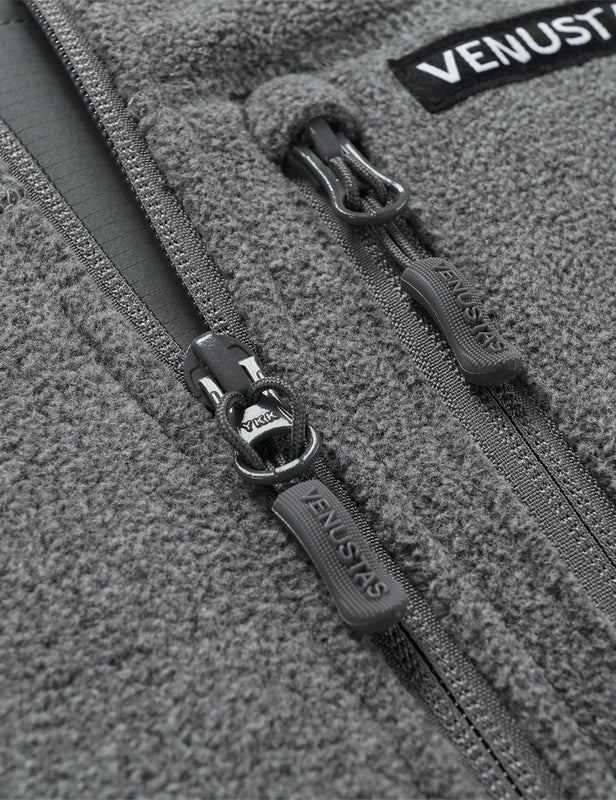 Close-up of gray fleece vest front zipper pulls and chest pocket