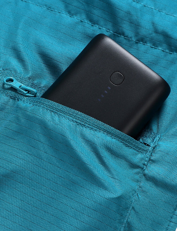 Black battery pack tucked into a teal heated vest zipper pocket